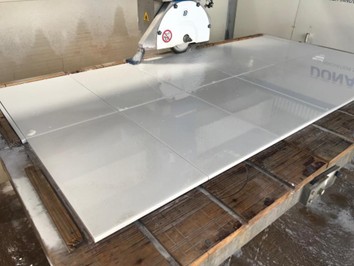 Stone cutting machinery operations worker operating CNC equipment manufacturing facility